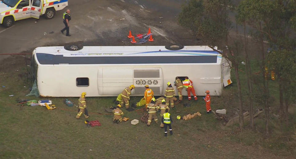 A bus lies on its side as emergency workers enter through the roof to try and help trapped children escape. 