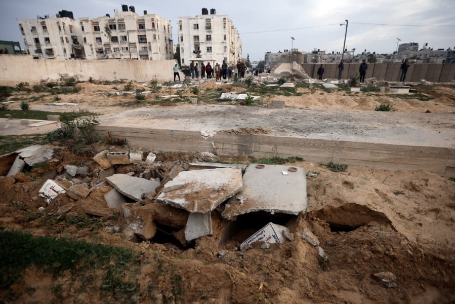 Palestinians inspect damaged graves following an Israeli tank raid over a cemetery in Khan Younis refugee camp, southern Gaza Strip, Wednesday, Jan. 17, 2024. (AP Photo/Mohammed Dahman)