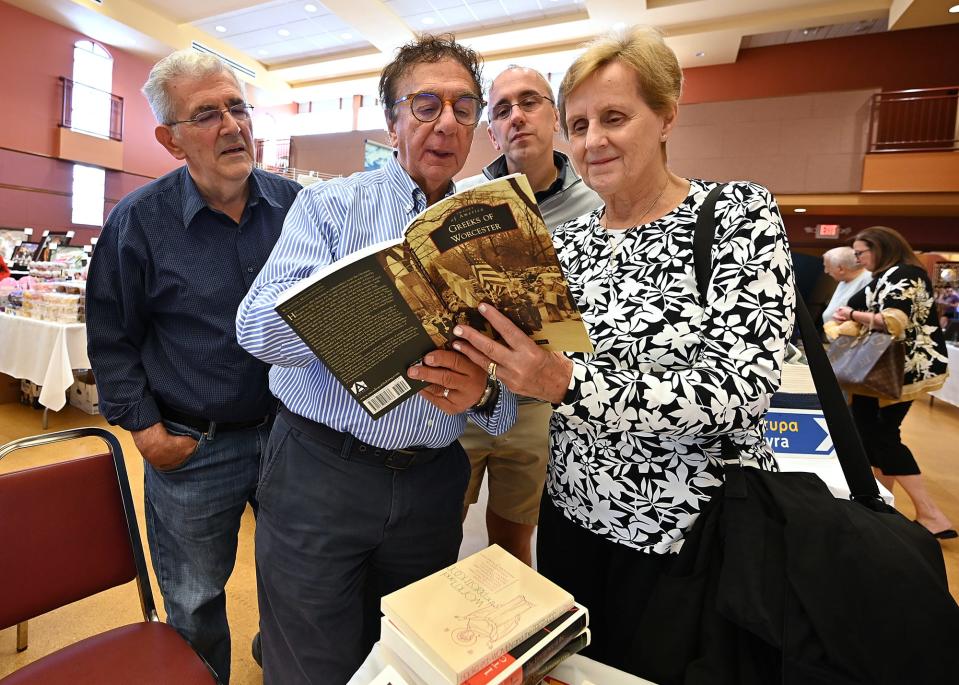 Florence Barris of Worcester, and her son, Chris, background center, learn that they are cousins to Matthew Panagioto, center, as he shows them the book "Greeks of Worcester" at the Agora Marketplace during Saturday's Grecian Festival at St. Spyridon Greek Orthodox Cathedral. Looking on at left, is Worcester historian and author, Kosta Ganias.