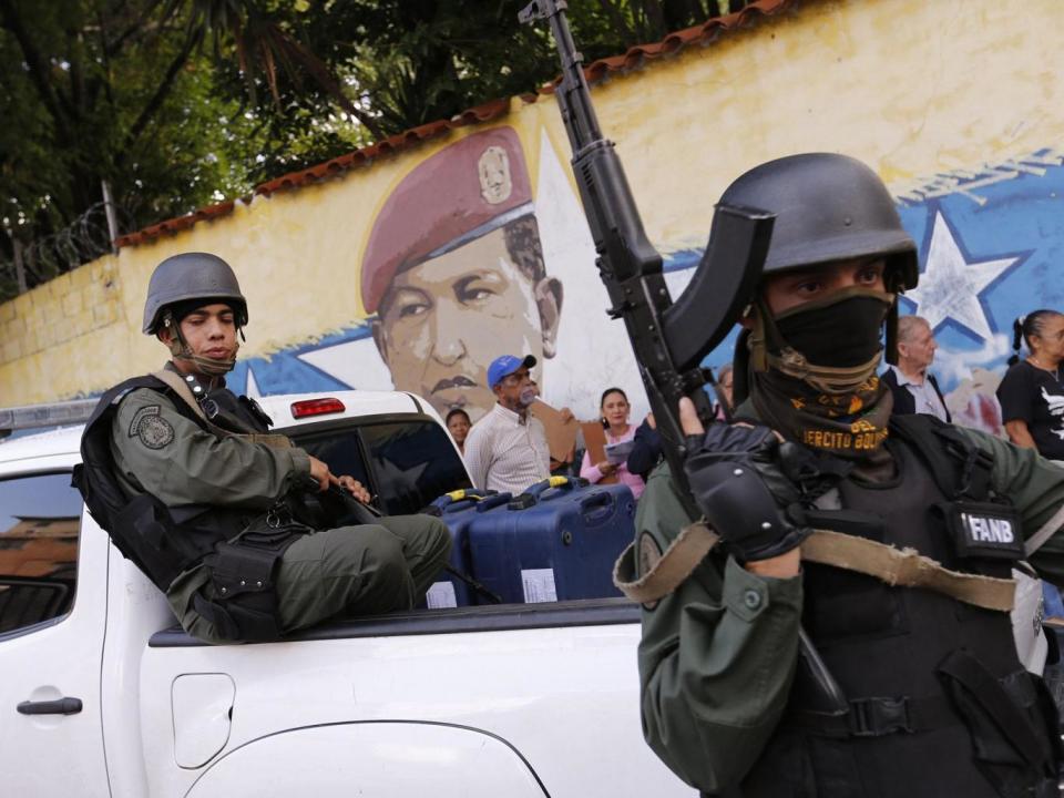 Soldiers stand guard as people wait in line in front of a mural of the late Venezuelan President Hugo Chavez before casting their votes at a polling station during the Constituent Assembly election in Caracas, Venezuela (REUTERS/Andres Martinez Casares)