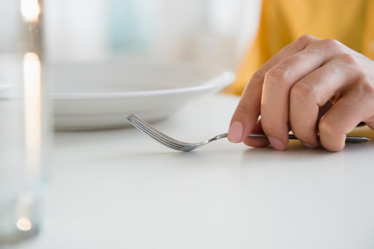 Close up of mixed race man holding fork at table