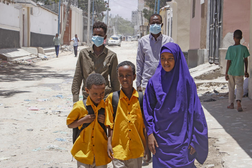 Somali schoolchildren walk home, while other people wear surgical masks, after the government announced the closure of schools and universities and banned large gatherings, following the announcement on Monday of the country's first case of the new coronavirus, in the capital Mogadishu, Somalia Wednesday, March 18, 2020. For most people, the new coronavirus causes only mild or moderate symptoms such as fever and cough and the vast majority recover in 2-6 weeks but for some, especially older adults and people with existing health issues, the virus that causes COVID-19 can result in more severe illness, including pneumonia. (AP Photo/Farah Abdi Warsameh)