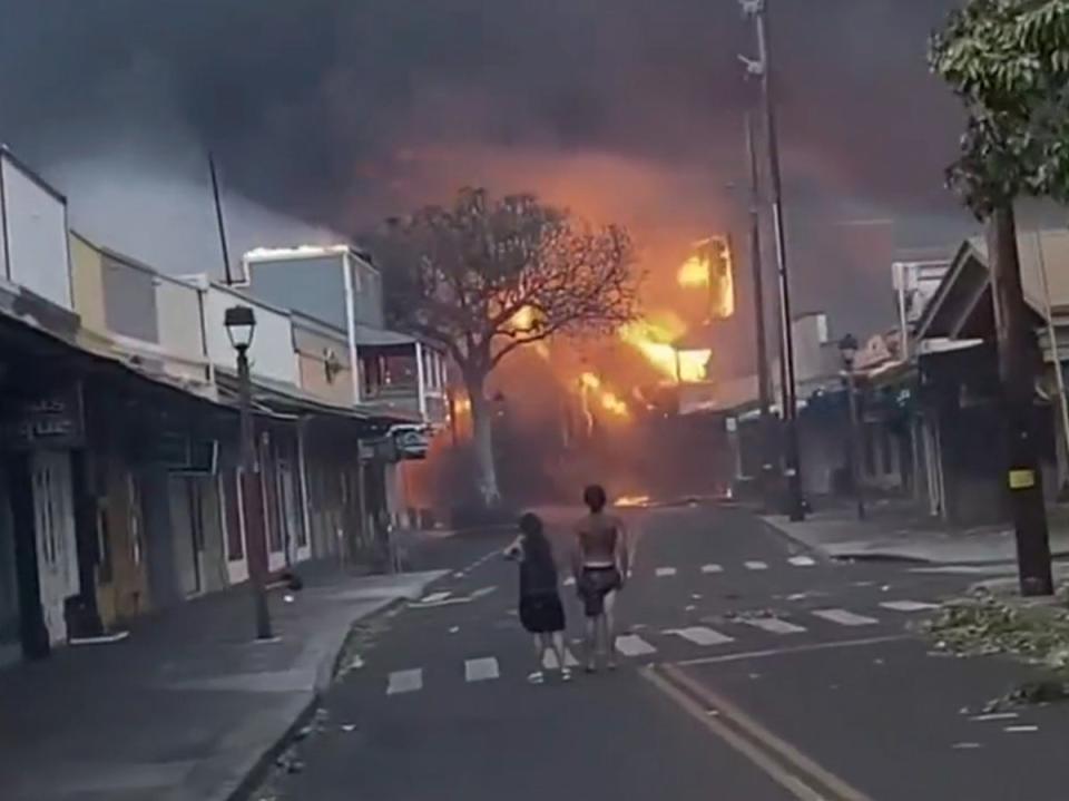 People watch as smoke and flames fill the air from raging wildfires on Front Street in downtown Lahaina, Maui on 9 August (Alan Dickar via AP)