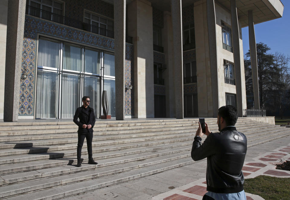 In this Tuesday, Jan. 15, 2019 photo, men take pictures while visiting Niavaran Palace, now a museum, that was the primary and last residence of late Shah Mohammad Reza Pahlavi and his family prior to leaving Iran for exile during the 1979 Islamic Revolution, in northern Tehran, Iran. The palace complex of mansions on a 27-acre plot, nestled against the Alborz Mountains, now welcomes the public to marvel at the luxuries the shah enjoyed as Iran's monarch for nearly four decades. It costs about $1 to enter. (AP Photo/Vahid Salemi)