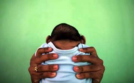 Jackeline Vieira de Souza, 26, holds her four-month-old son Daniel who was born with microcephaly in front of their house in Olinda, near Recife, Brazil, February 11, 2016. REUTERS/Nacho Doce/Files