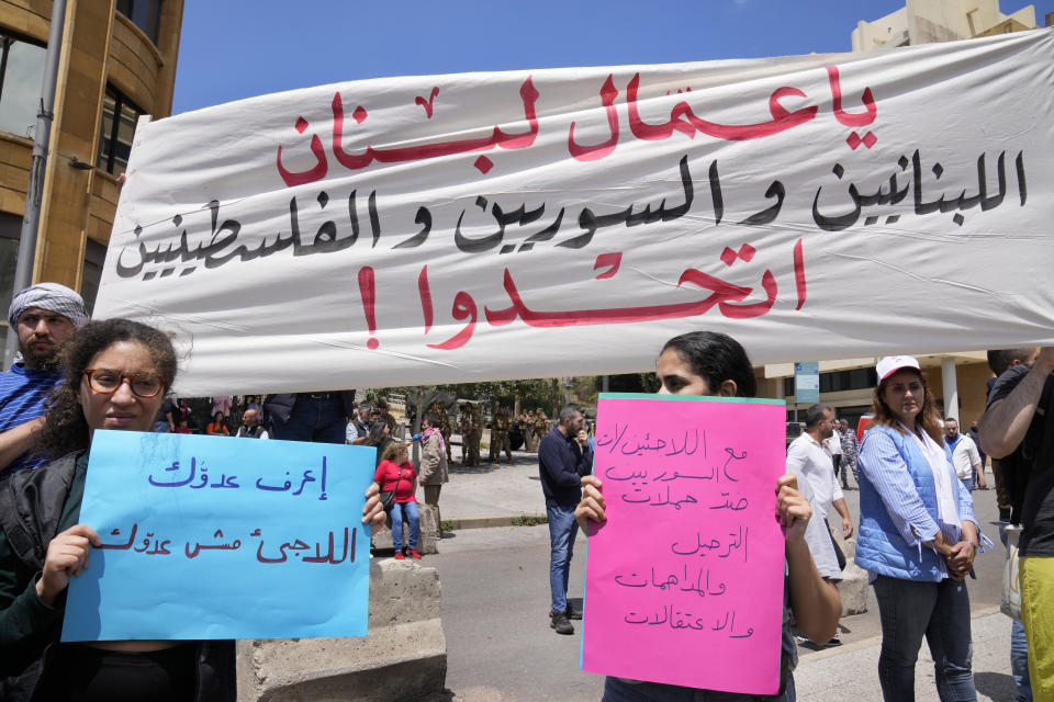 Protesters hold a banner reading "Lebanese, Syrian and Palestinian workers of Lebanon, unite" and signs expressing solidarity with refugees and opposition to forcible deportation at a workers' day march held by leftist groups in Beirut, Lebanon, Monday, May 1, 2023. The slogans came in response to increased pressure by Lebanese authorities on Syrian refugees in recent weeks, including raids, arrests and deportations. (AP Photo/Hussein Malla)