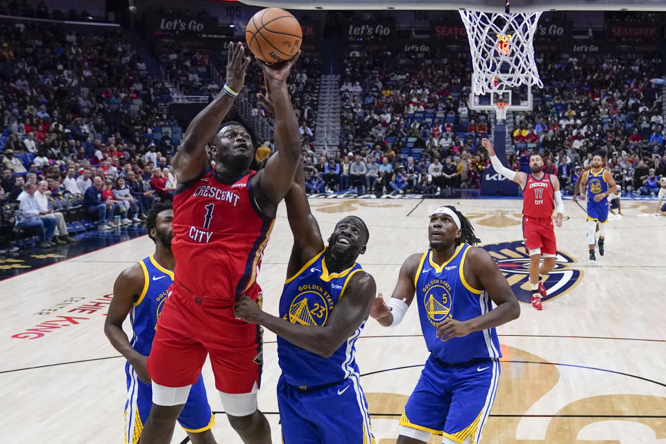 New Orleans Pelicans forward Zion Williamson (1) goes to the basket over Golden State Warriors forward Draymond Green (23) and forward Kevon Looney (5) in the first half of an NBA basketball game in New Orleans, Monday, Oct. 30, 2023. (AP Photo/Gerald Herbert)