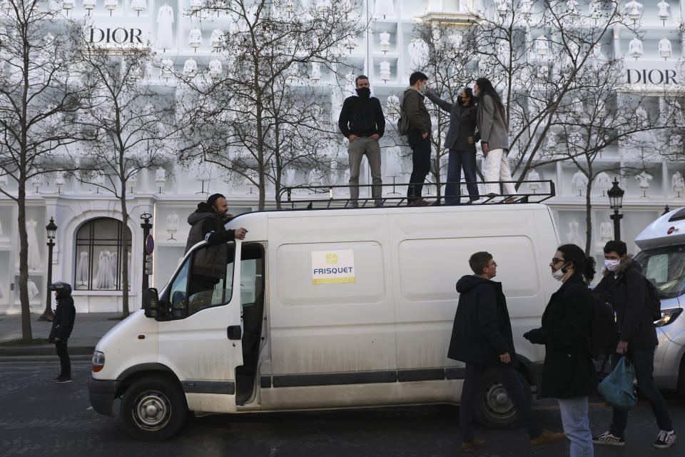 Protesters stand atop a van during p rotest on the Champs-Elysees avenue, Saturday, Feb.12, 2022 in Paris. Paris police intercepted at least 500 vehicles attempting to enter the French capital in defiance of a police order to take part in protests against virus restrictions inspired by the Canada's horn-honking "Freedom Convoy." . (AP Photo/Adrienne Surprenant)