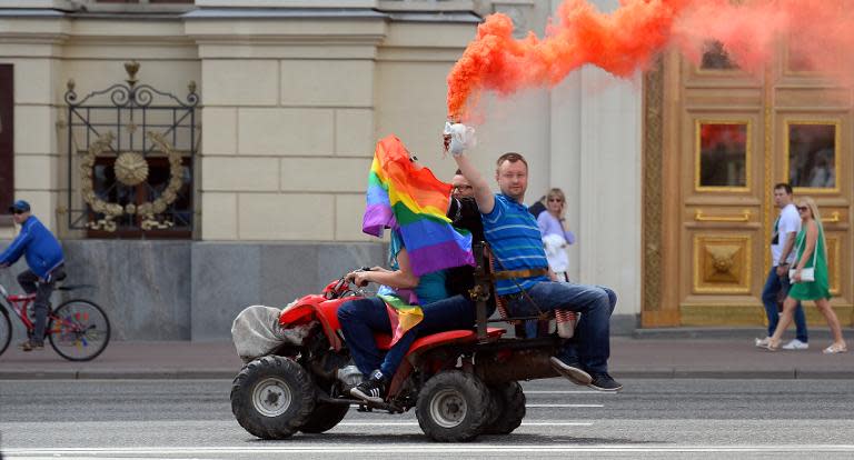 Gay and LGBT rights activist Nikolai Alexeyev (R) holds a flare as he rides a quad-bike during an unauthorized gay rights activists rally in central Moscow on May 30, 2015