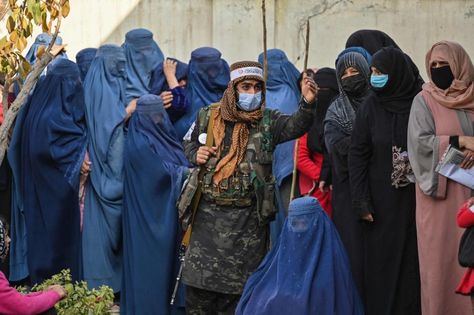 File photo: A Taliban fighter stands guard as women wait in a queue during a World Food Programme cash distribution in Kabul, Afghanistan, 29 November 2021 (AFP via Getty Images)
