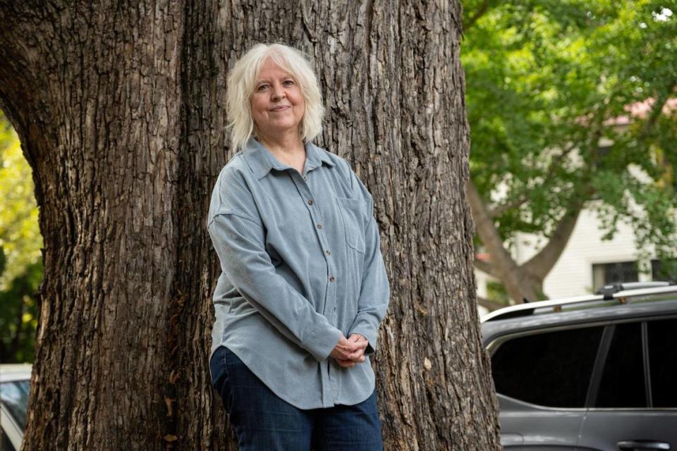 Susan Christian stands earlier this month in front of the trunk of the California elm tree that she wants to save on her property in Sacramento’s Boulevard Park. The city is considering cutting down the tree for safety, but an arborist hired by Christian believes that only part of it needs to be removed. Paul Kitagaki Jr./pkitagaki@sacbee.com