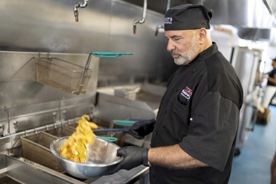 Executive chef John Bordieri prepares a dish of calamari at Iggy's Boardwalk restaurant Friday, June 7, 2024, in Warwick, R.I. This year, the "calamari comeback" chef might not be coming back. Bordieri became known as the "calamari ninja" for standing wordlessly, clad head-to-toe in black, and holding a platter of sauteed squid during a video roll call of states that nominated Joe Biden during the 2020 Democratic National Convention. But he now says he hasn't heard from state or national leaders about a repeat performance at this summer's party's convention in Chicago. (AP Photo/David Goldman)