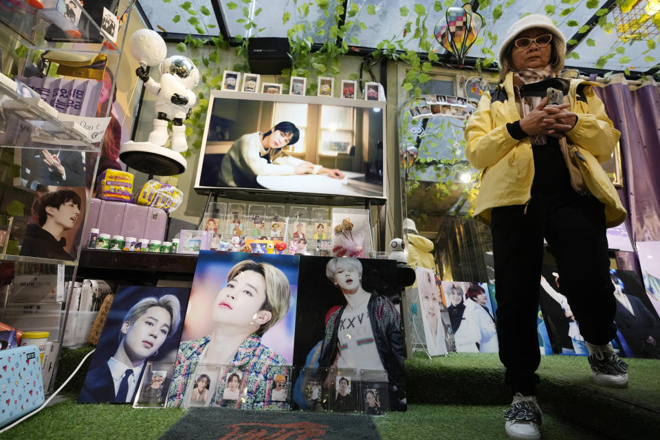 A woman passes by images of members of South Korean K-pop band BTS at a cafe in Seoul, South Korea, Monday, Dec. 11, 2023. Singers RM and V of the K-pop band BTS began their mandatory military duties under South Korean law, their management agency announced Monday. This came a day before two of their bandmates, Jimin and Jung Kook, were also expected to report for duty. (AP Photo/Ahn Young-joon)