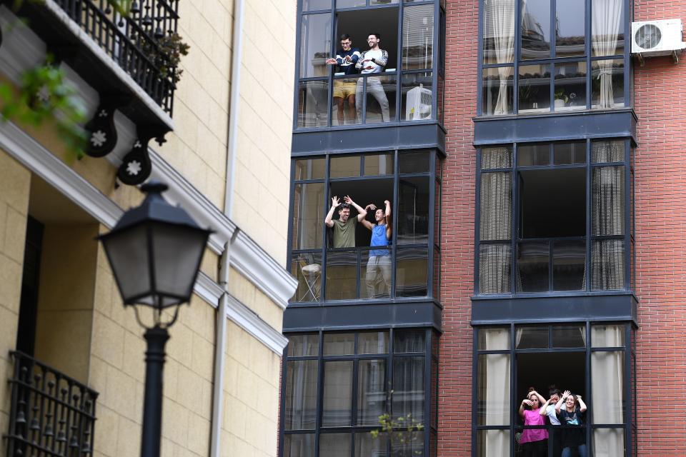 Varios vecinos de un bloque de Madrid salen a sus balcones a cantar y bailar. (Foto: Gabriel Bouys / AFP / Getty Images).