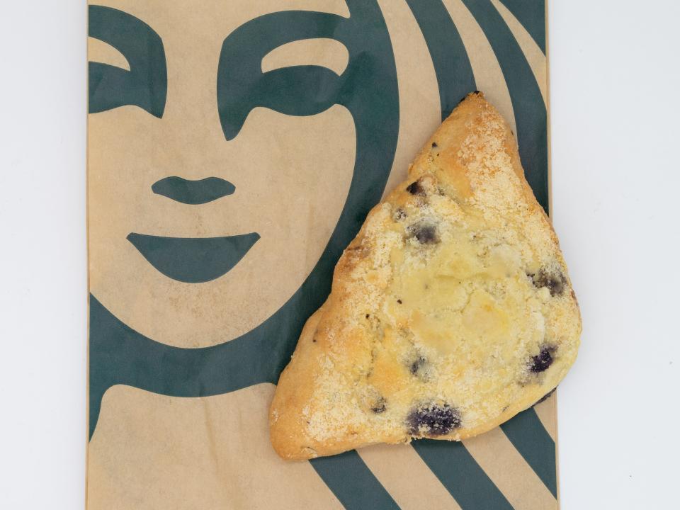 triangular blueberry scone sitting on top of a brown starbucks pastry bag