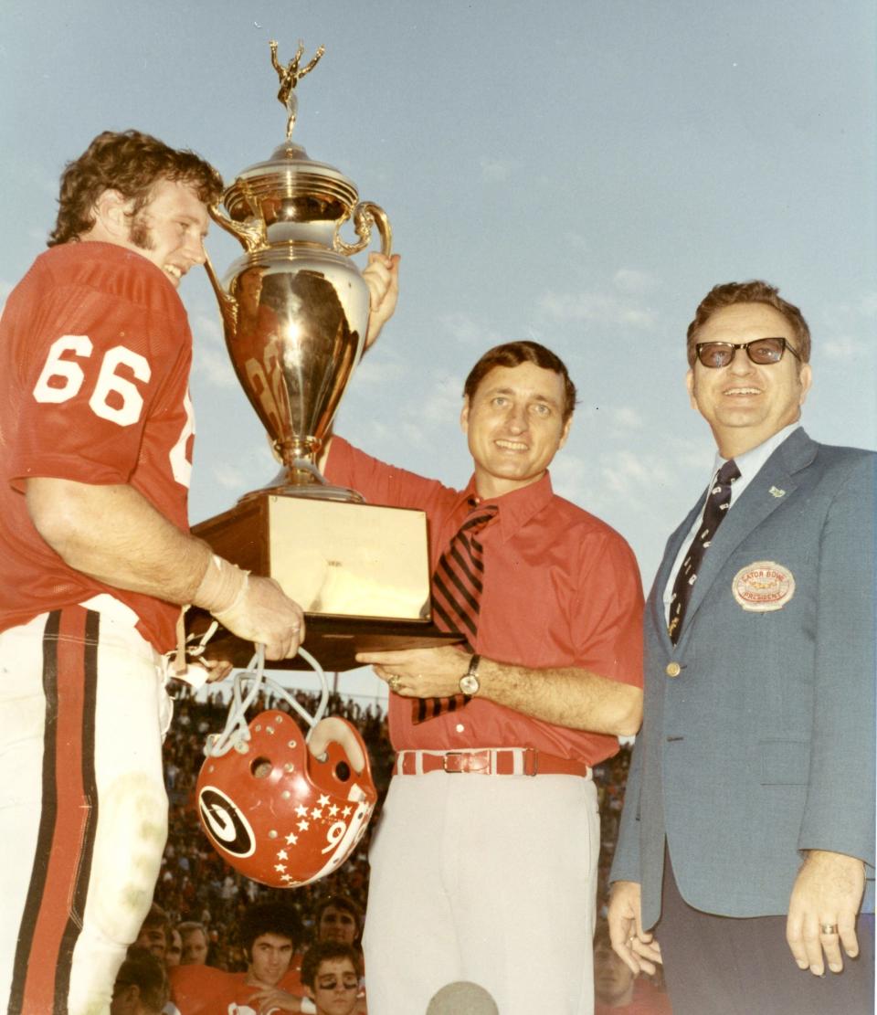Georgia coach Vince Dooley and captain Royce Smith (66) accept the Gator Bowl championship trophy after beating North Carolina 7-3 on Dec. 31, 1971. Gator Bowl president W.W. Gay is on the right.