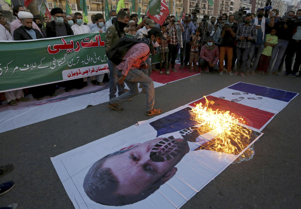 Pakistani Shiite Muslims burn a representation of a French flag and a defaced image of French President Emmanuel Macron during a rally against the French president and the republishing of caricatures of the Prophet Muhammad they deem blasphemous, near the French consulate in Karachi, Pakistan, Sunday, Nov. 1, 2020. (AP Photo/Fareed Khan)