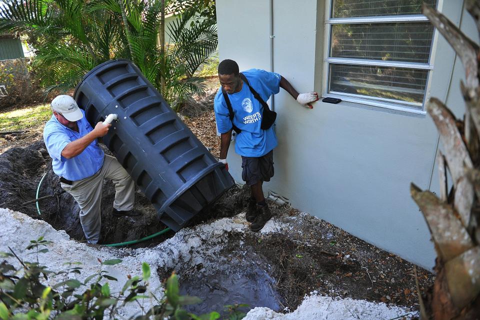 Cornelius Kossen (left) of the Stuart Public Works Department and Holwinster Alexis install a grinder tank in 2015 at a home on Osceola Street in Stuart. The system, which could be used if neighborhoods in northern Sewall's Point vote to switch from septic tanks to the Martin County sewer system, grinds sewage which is pumped through a 1.25-inch hose also buried in the yard into an established sewer line.