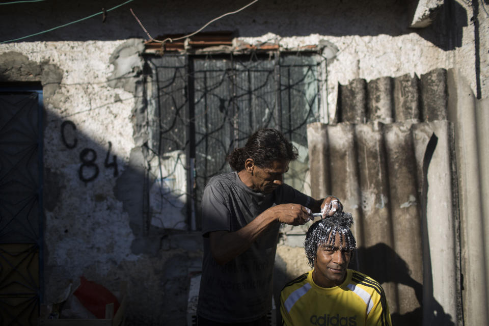 In this Jan. 10, 2014 photo, a residnet gets his hair done inside the Favela do Metro slum in Rio de Janeiro, Brazil. Some residents in this slum were evicted from their homes two years ago for the area to be renovated for this year's World Cup and 2016 Olympics, but people reoccupied the homes and are fighting to stay. (AP Photo/Felipe Dana)