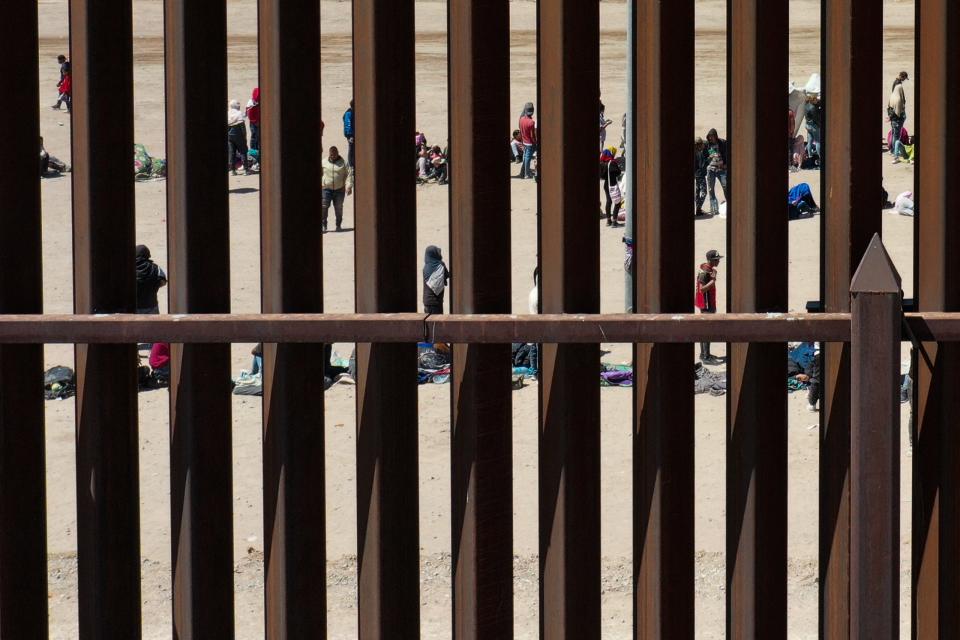 Migrants wait along the border wall to surrender to US Customs and Border Protection agents for immigration and asylum claim processing after crossing the Rio Grande River into the United States in May.