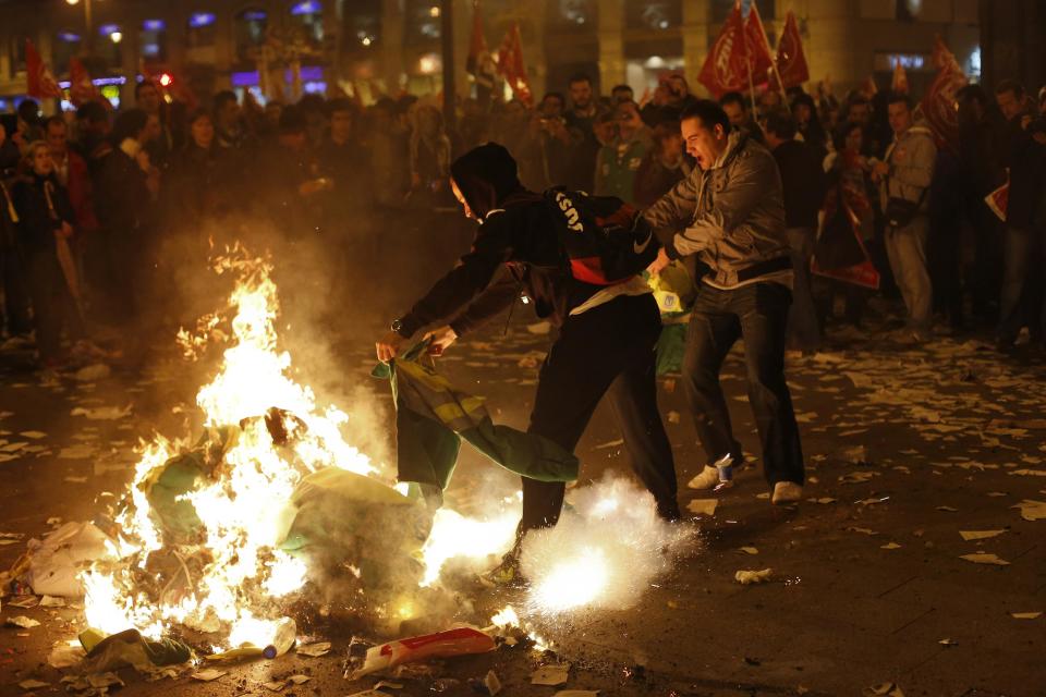 Protesters throw cleaning worker jackets in a fire during a protest at Madrid's Puerta del Sol square