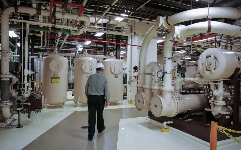 FILE - An employee walks past equipment in the turbine building at the Oyster Creek nuclear plant in Lacey Township, N.J., Feb. 25, 2010. For the second time in as many months, the U.S. Nuclear Regulatory Commission has fined the owners of the former New Jersey nuclear power plant for security-related violations. The agency on Wednesday, jan. 26, 2022 said it fined Holtec Decommissioning International $50,000 for security violations at the former Oyster Creek nuclear power plant in Lacey Township. (AP Photo/Mel Evans, File)