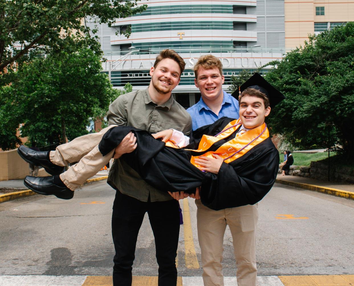 Miles (left) and Coleman Kredich (right) holding up Ben Kredich in front of Neyland Stadium.
