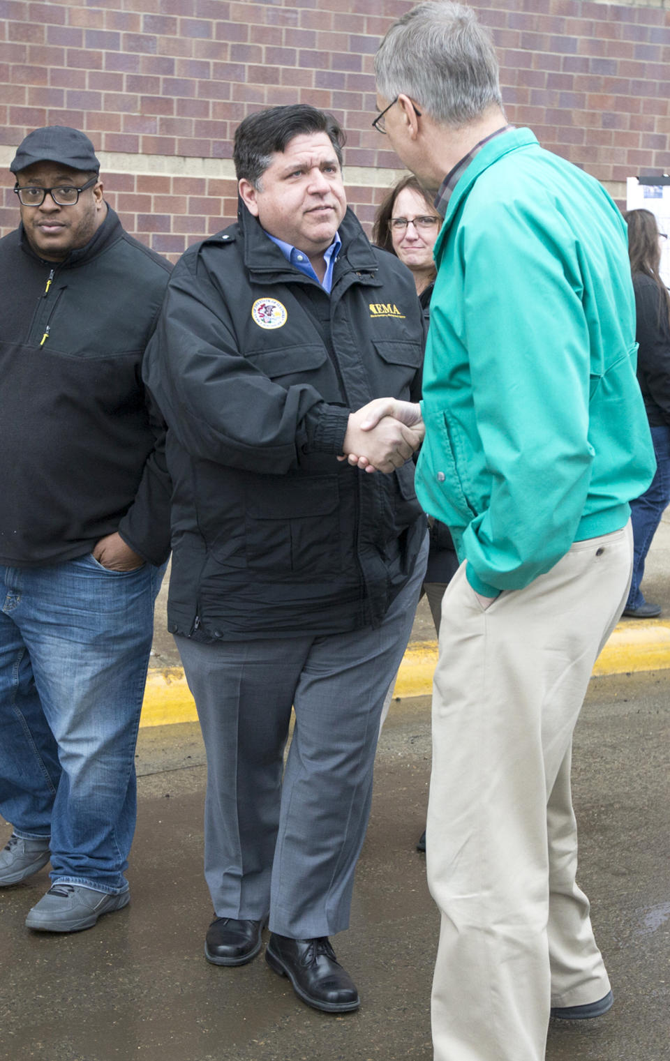 FILE--In this March 20, 2019 file photo, Gov. J.B. Pritzker, center, speaks with Bill Hadley, the Stephenson County Board Chairman, right, and Pastor Antwon Funches of St. Paul Missionary Baptist Church, left, during a stop to survey flood damage in Freeport, Ill. During his first six weeks in office, Pritzker’s appointment calendar includes 70 “attire” recommendations for events as varied as bill signings, a state police officer’s funeral, a White House dinner, surveying flood damage, and cocktails with legislators at the Illinois Governor’s Mansion. (Scott P. Yates/Rockford Register Star via AP, File)