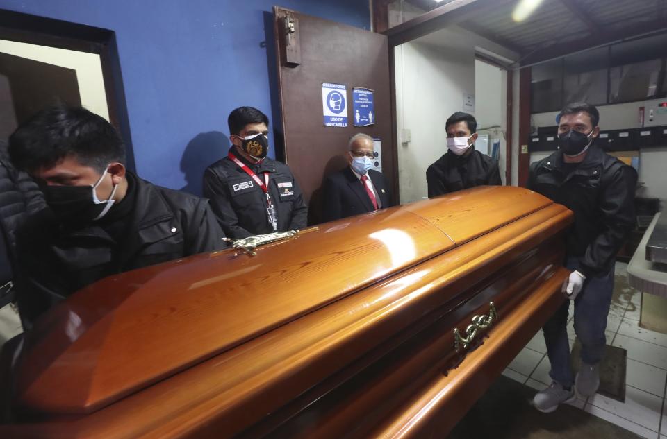 In this photo provided by Peru's Interior Ministry, Justice Minister Anibal Torres, second from left, watches police push the coffin of Abimael Guzman, founder and leader of the Shining Path guerrilla movement, at a crematorium in Callao, Peru, Friday, Sept. 24, 2021. The Peruvian government cremated Guzman on Friday, according authorities. (Rolly Reyna/Peruvian Interior Ministry via AP)