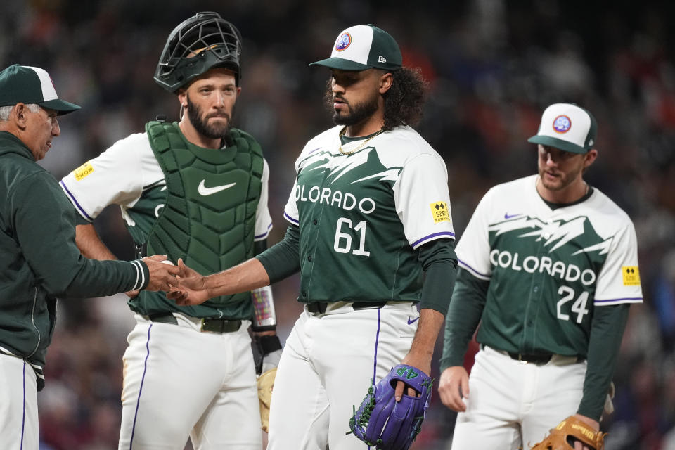 Colorado Rockies manager Bud Black, left, takes the ball from relief pitcher Justin Lawrence as catcher Jacob Stallings and third baseman Ryan McMahon, right, watch during the ninth inning of the team's baseball game against the Philadelphia Phillies on Saturday, May 25, 2024, in Denver. (AP Photo/David Zalubowski)