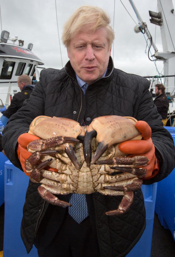 Boris Johnson holds a crab caught on the Carvela at Stromness Harbour