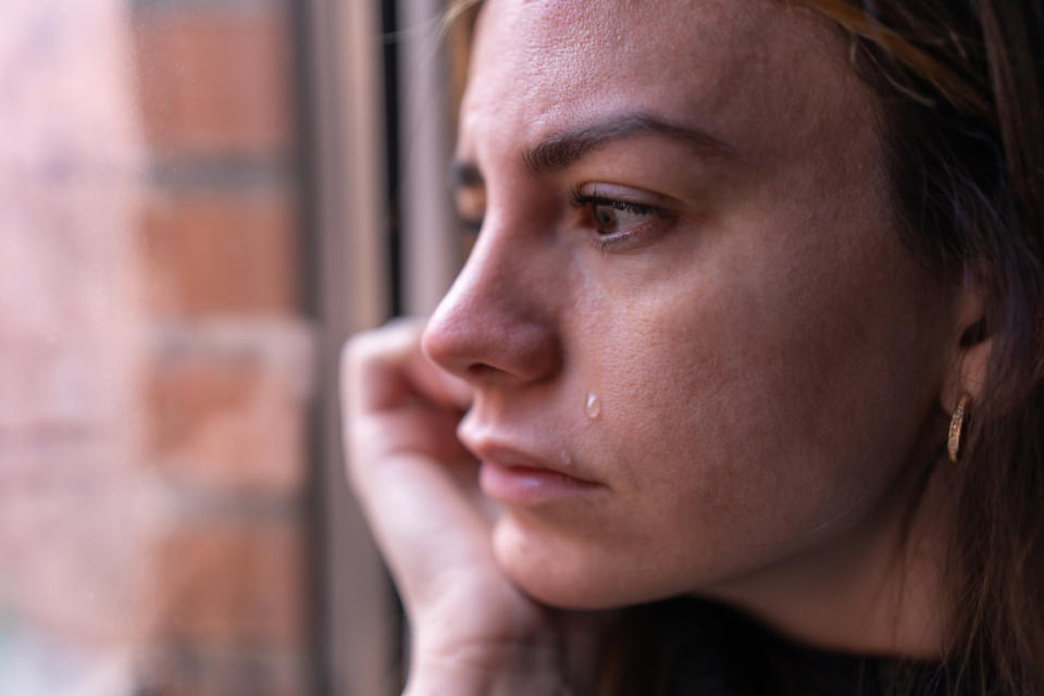 Close-up of a person with a tear rolling down their cheek, looking thoughtful or sad