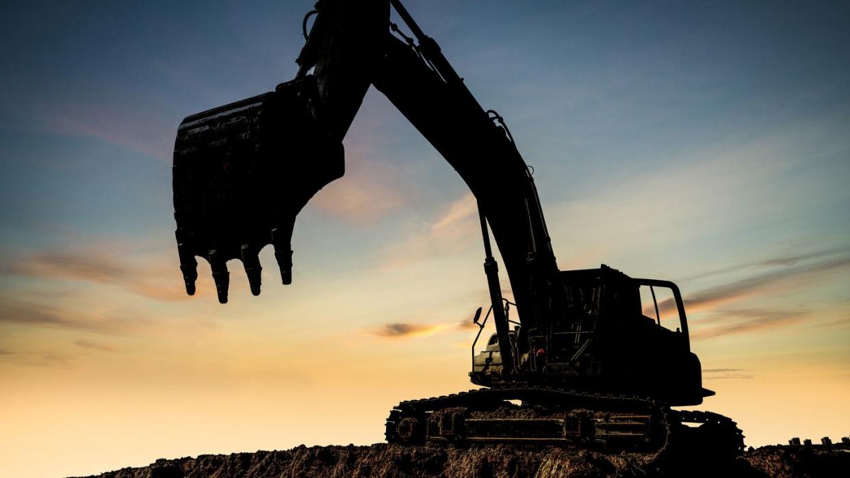 excavator at a construction site against the setting sun