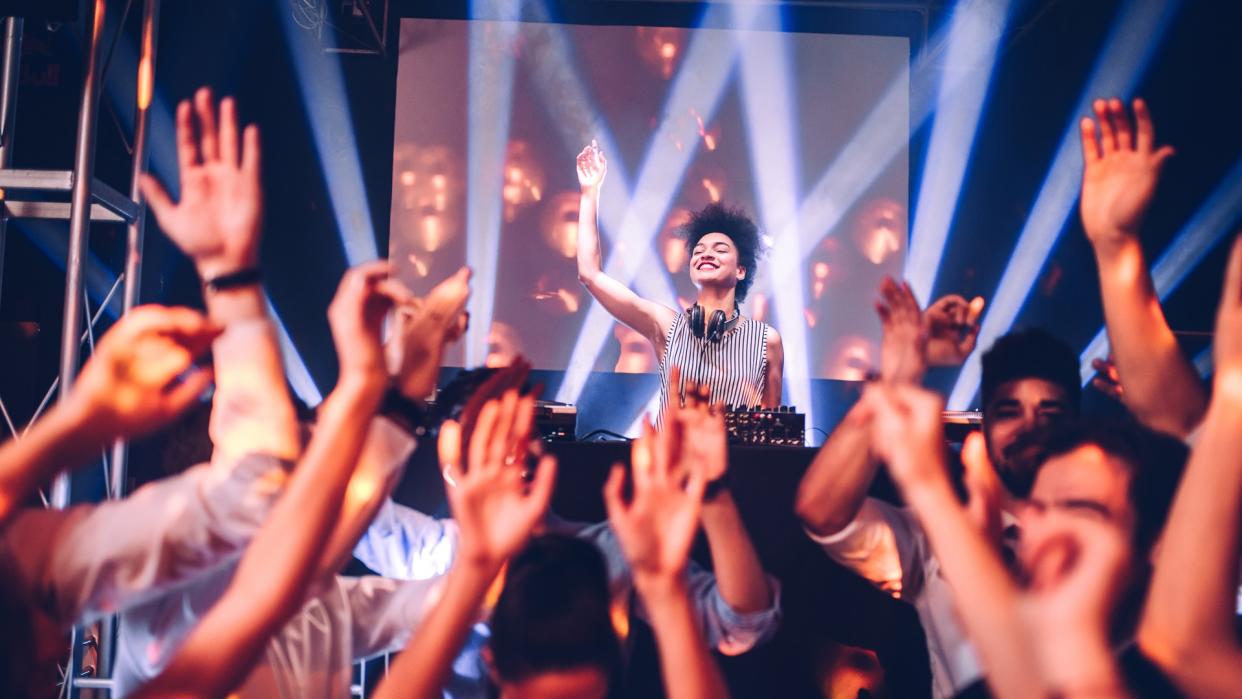 Shot of a female DJ playing music in the club.