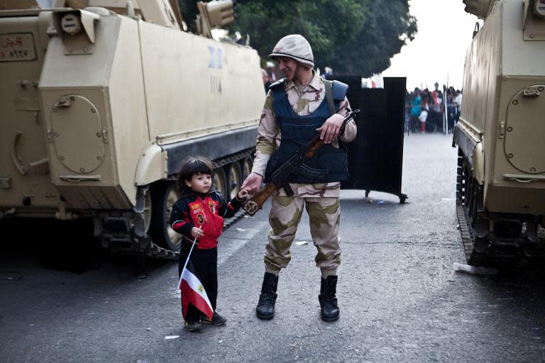 An Egyptian soldier holds the hand of a child in Cairo's Tahrir Square during a rally marking the anniversary of the 2011 uprising on January 25, 2014