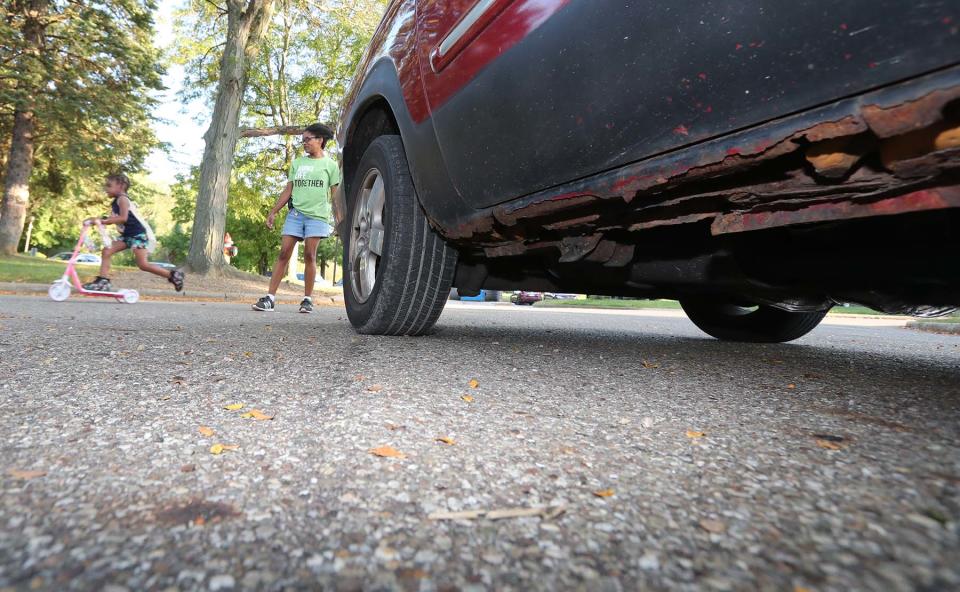 In this file photo from August 2022, Terah Coleman keeps an eye on her daughter Aliyah at their apartment complex in Green as her old car that is parked in the foreground shows it wear and tear with rust issues, among other problems.