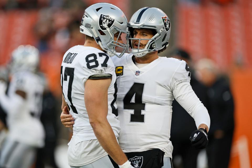 Las Vegas Raiders quarterback Derek Carr (4) talks with tight end Foster Moreau (87) before an NFL football game against the Cleveland Browns, Monday, Dec. 20, 2021, in Cleveland. (AP Photo/Ron Schwane)