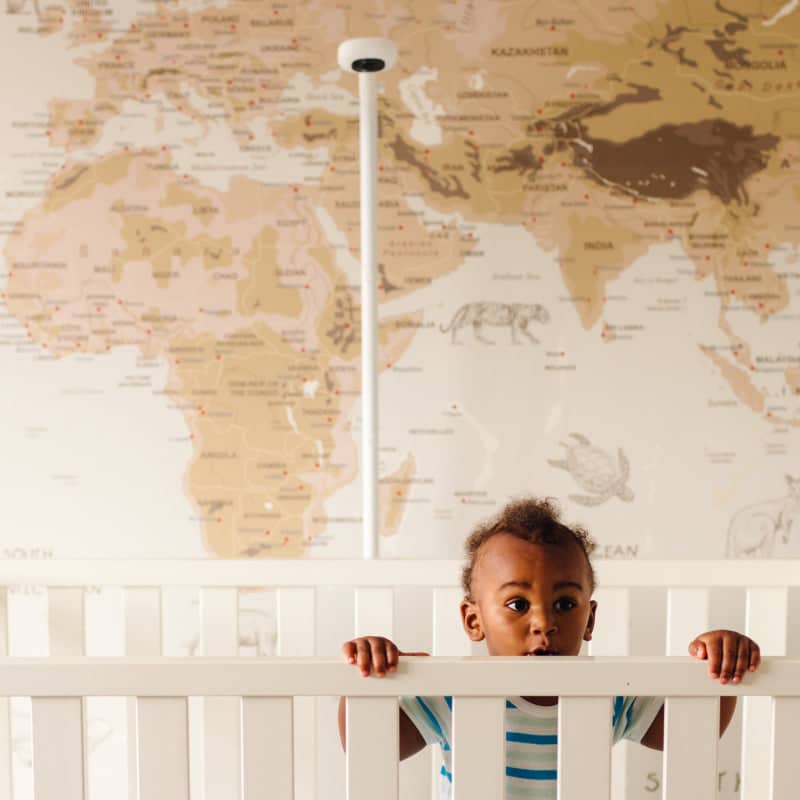 Toddler in white crib with map behind him