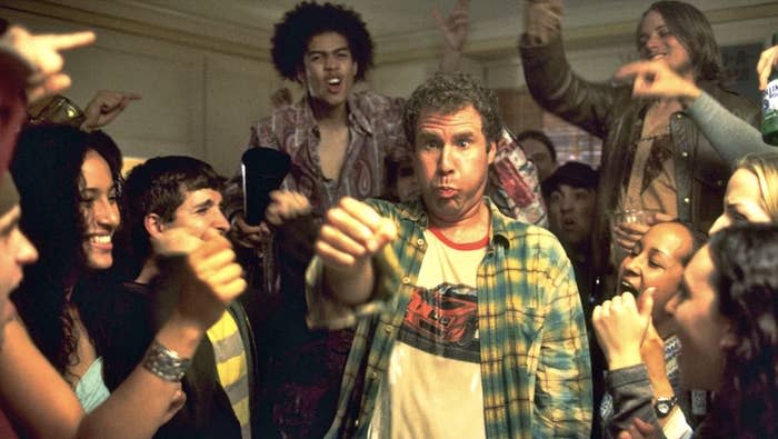 A man in a flannel shirt looks surprised at a lively party as people cheer around him