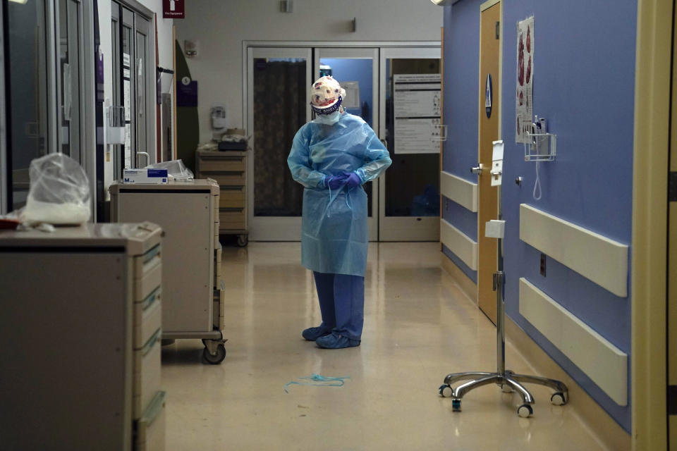 Registered nurse Anita Grohmann puts on her PPE in a COVID-19 unit at St. Joseph Hospital in Orange, Calif. Thursday, Jan. 7, 2021. California health authorities reported Thursday a record two-day total of 1,042 coronavirus deaths as many hospitals strain under unprecedented caseloads. The state's hospitals are trying to prepare for the possibility that they may have to ration care for lack of staff and beds — and hoping they don't have to make that choice. (AP Photo/Jae C. Hong)