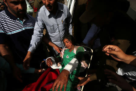 People shift a woman, who according to local media was injured in what they say was a ceasefire violation by the Pakistani troops along the Line of Control (LOC) in Poonch district, towards a government hospital in Jammu, March 18, 2018. REUTERS/Mukesh Gupta