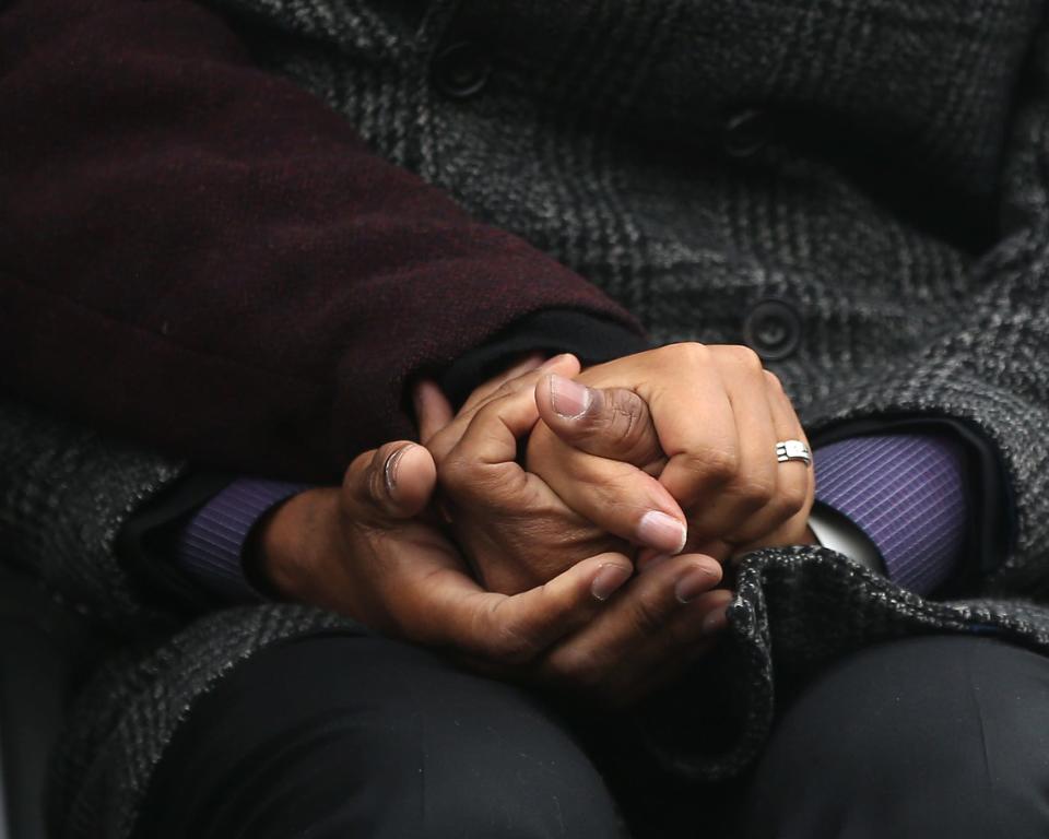 A man and a woman hold hands during the unveiling ceremony of "The Embrace," a sculpture dedicated Friday to the Rev. Martin Luther King Jr. and Coretta Scott King on Boston Common.