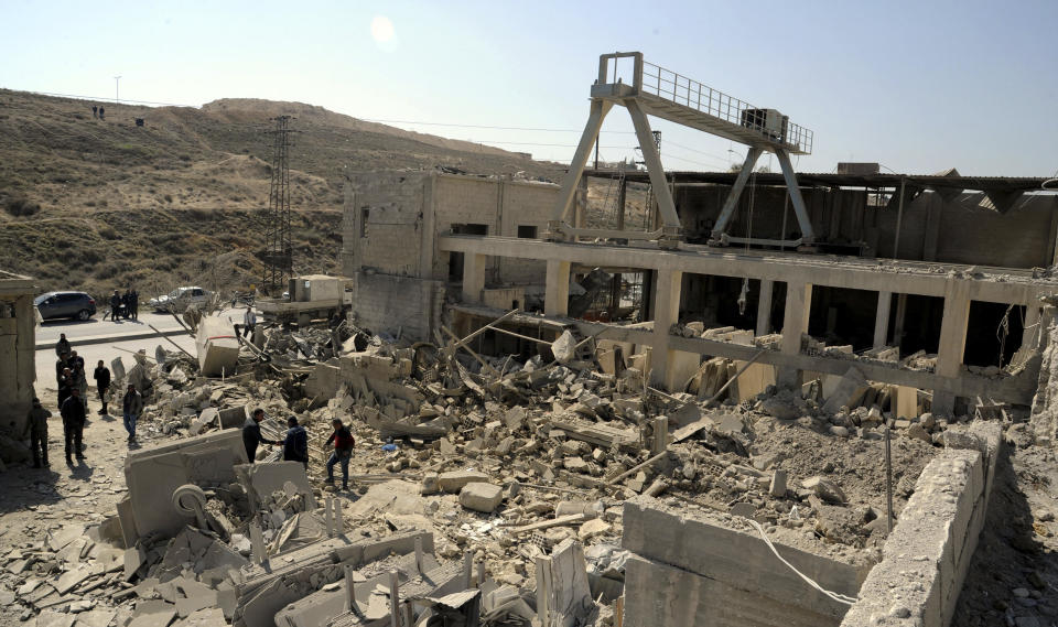 In this photo released by the Syrian official news agency SANA, people inspect damage after an Israeli airstrike near Damascus, Syria, Monday, March 7, 2022. Israel fired several missiles toward Syrian military positions near the capital Damascus Monday, killing two civilians and causing material damage, Syria's defense ministry said. It was the first Israeli attack inside Syria since Russia, a key backer of President Bashar Assad, invaded Ukraine. (SANA via AP)