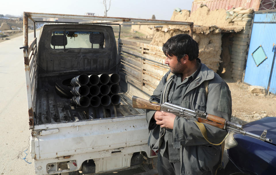 An Afghan security person sand near a vehicle in which rockets were placed, in Bagram, north of Kabul, Afghanistan, Saturday, Dec. 19, 2020. Five rockets were fired at a major U.S. base in Afghanistan on Saturday, but there were no casualties, NATO and provincial officials said. (AP Photo/Rahmat Gul)