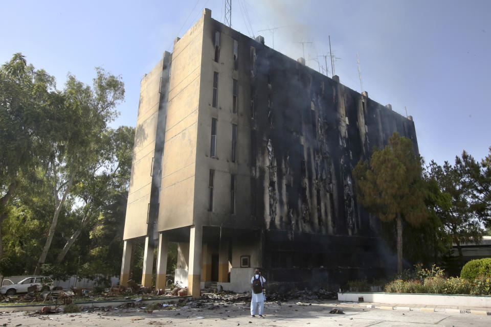 FILE - A member of the media takes photos of the burning building of the Radio Pakistan that was set on fire by angry supporters of Pakistan's former Prime Minister Imran Khan protesting against the arrest of their leader, in Peshawar, Pakistan, on May 10, 2023. Pakistan's Prime Minister Shehbaz Sharif on Thursday, May 25, 2023 vowed stern action against all those rioters who burned down an ancient radio station in the northwestern city of Peshawar earlier this month, drawing a nationwide condemnation. (AP Photo/Muhammad Sajjad, File)