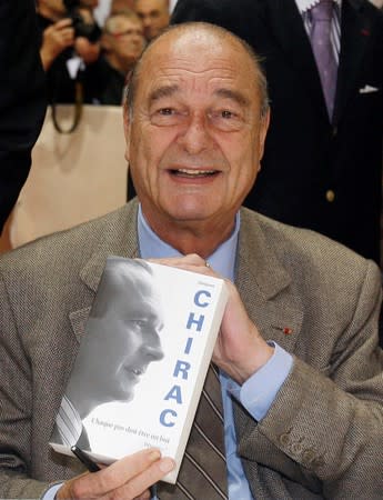 FILE PHOTO: Former French President Jacques Chirac holds up his book "Chaque pas doit etre un but" (Each Step Must Itself Be a Goal) during a book signing at the book fair of Brive la Gaillarde in central France