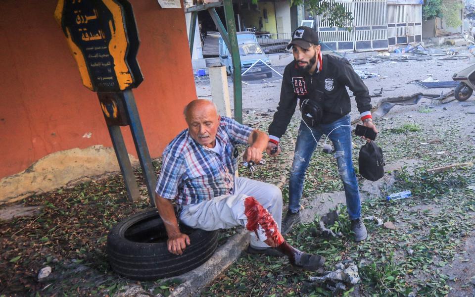 An injured resident sits on a sidewalk during Israeli airstrikes on the Mreijeh neighbourhood in Beirut's southern suburbs on Oct 4