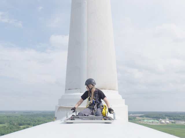 Wind tech Faith Lutat, 22, climbing out of the nacelle of a wind turbine at Iowa Lakes Community College in Estherville, Iowa.