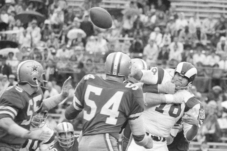 FILE - Los Angeles Rams quarterback Roman Gabriel, right, is hit by a host of Dallas Cowboys as the ball heads for the sidelines during the third period of an NFL Playoff Bowl football game, Jan. 3, 1970, in Miami, Fla. Gabriel, the former North Carolina State quarterback who was the 1969 NFL MVP with the Los Angeles Rams, died Saturday, April 20, 2024. He was 83. (AP Photo/File)