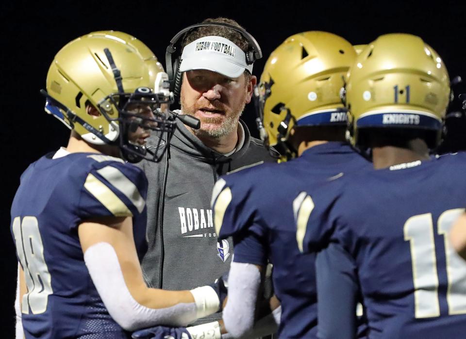 Hoban football coach Tim Tyrrell works a huddle with his team during the first half of a Division II home playoff game on Nov. 4, 2022.